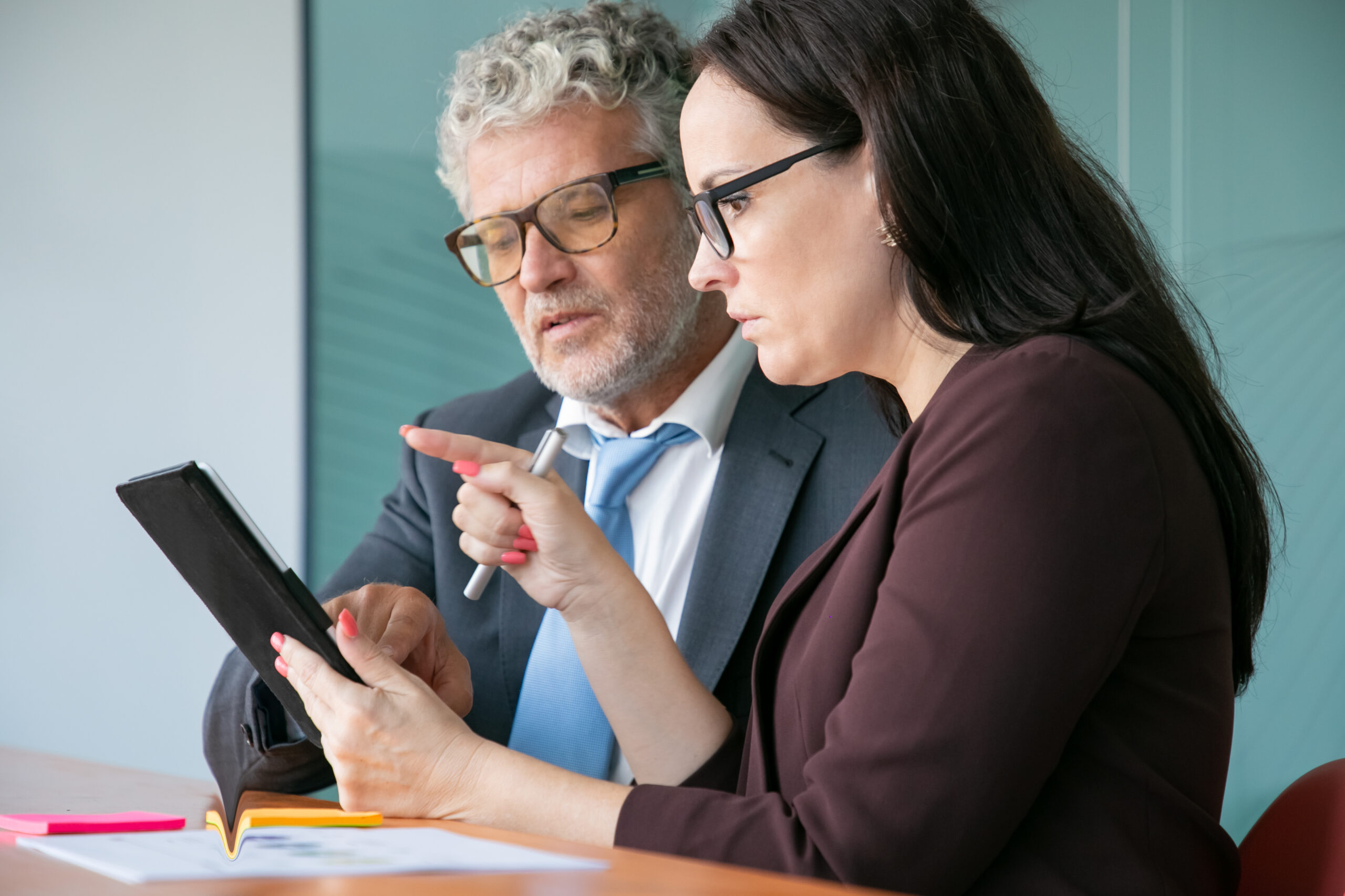 Two business professionals analyzing data on a tablet during a strategy meeting about regulatory reforms in financial institutions.