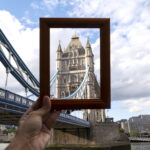 A hand holding a picture frame capturing the Tower Bridge in London, symbolizing the contrast between transparency and secrecy often associated with tax havens.