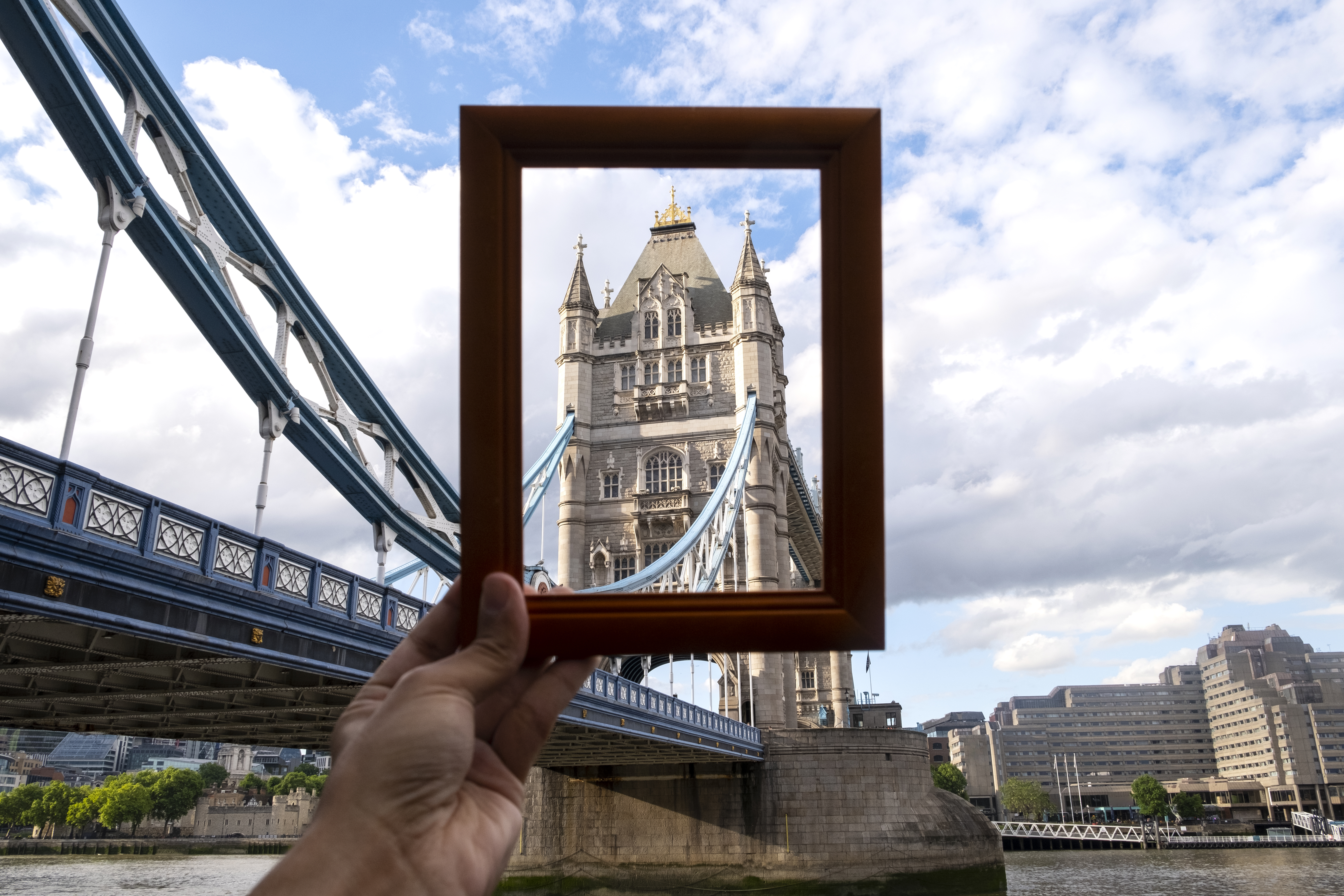 A hand holding a picture frame capturing the Tower Bridge in London, symbolizing the contrast between transparency and secrecy often associated with tax havens.
